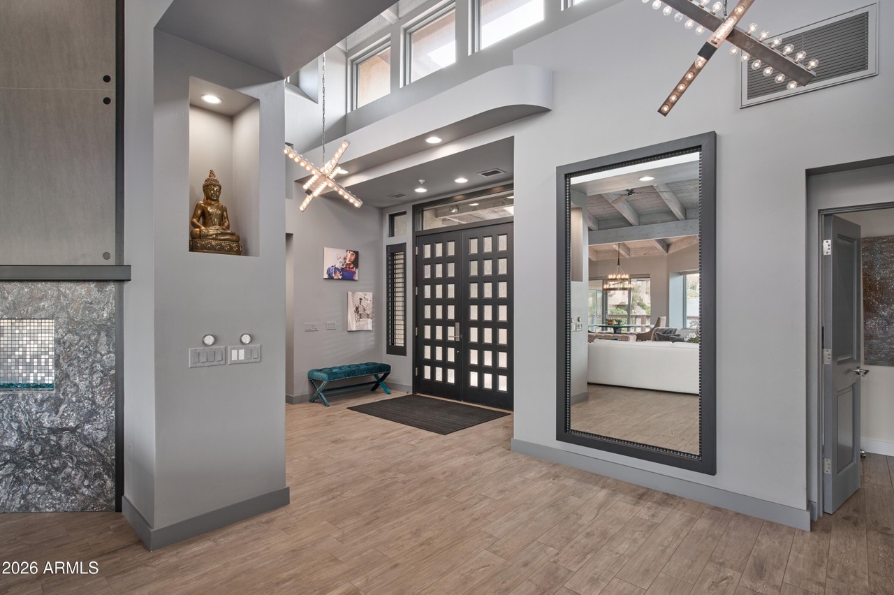 Grand entry foyer with double-height ceiling, spiral staircase, and modern chandeliers