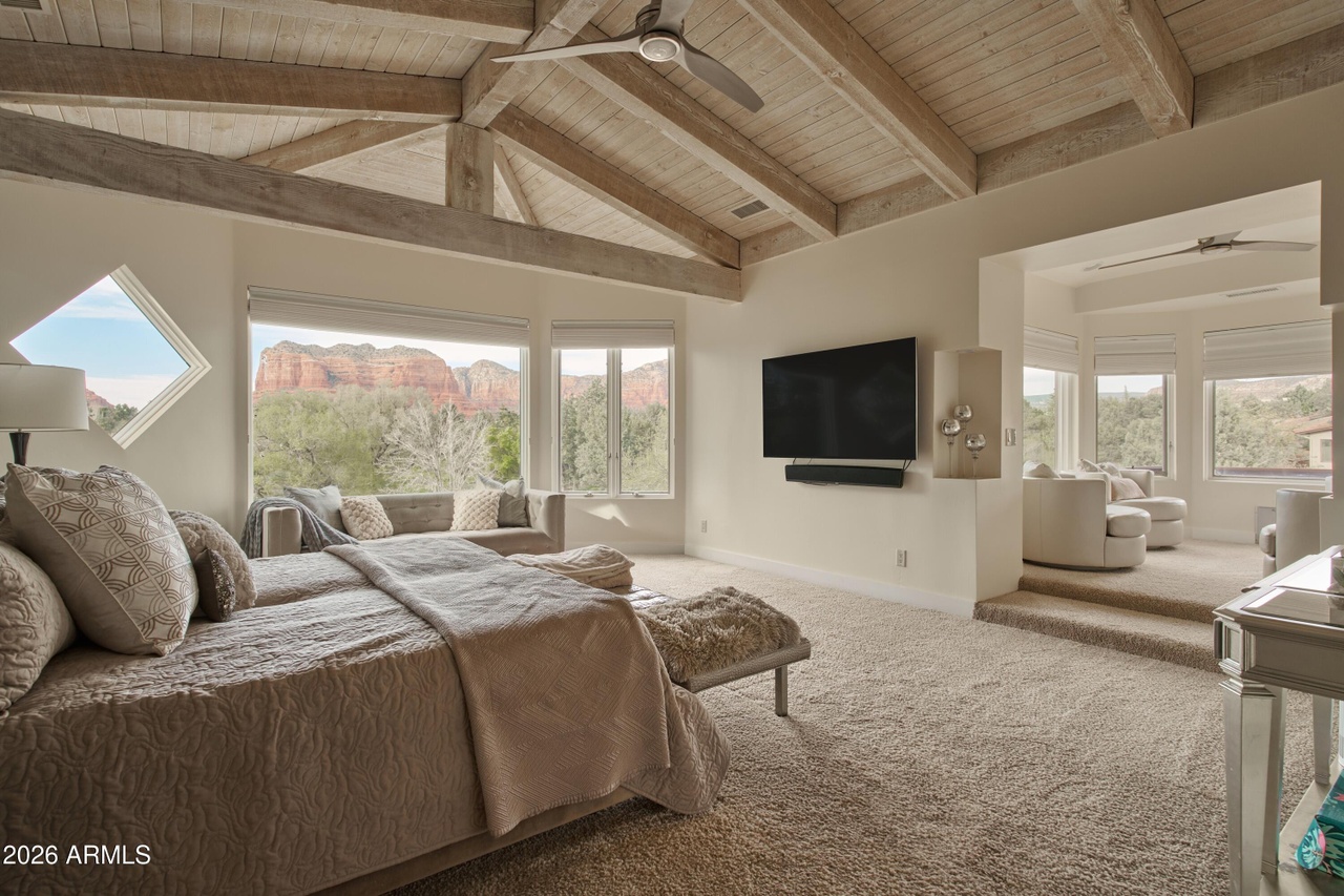 Primary bedroom with vaulted wood beam ceiling and panoramic red rock views
